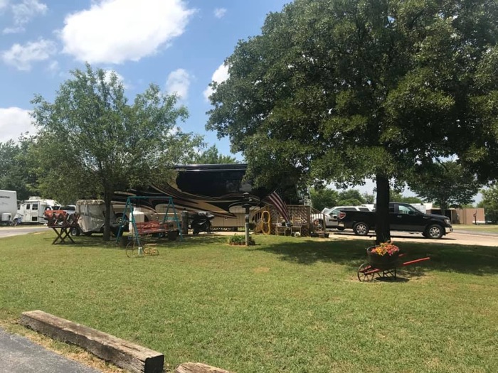 RV sites at ABC RV Park with green grass, shade trees and a fire ring