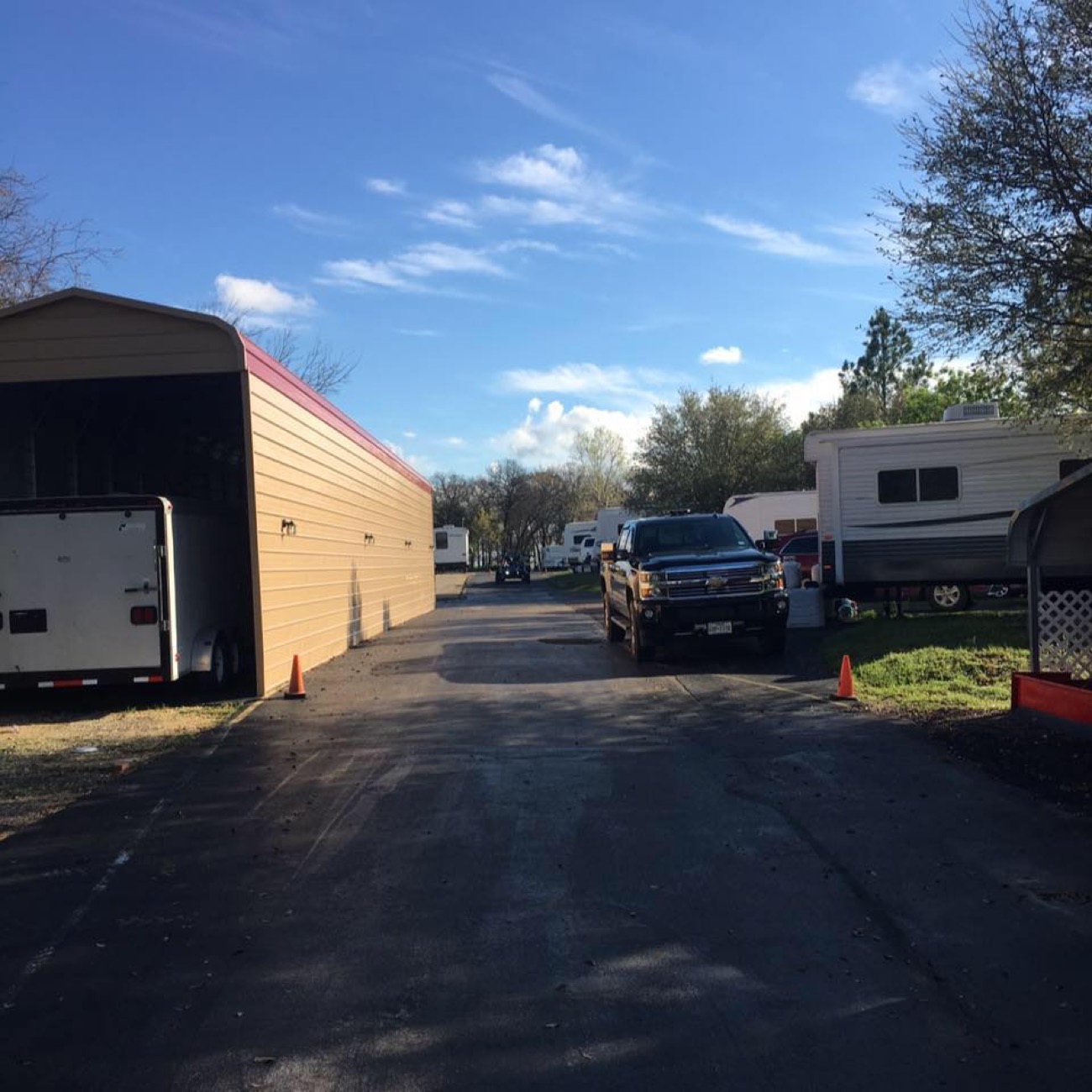 Wide paved lane through ABC RV Park lined with RVs and covered sites under a blue Texas sky