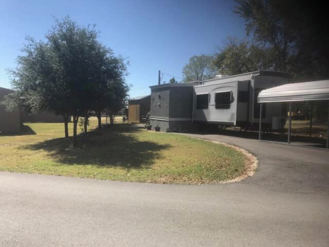 Shaded RV site at ABC RV Park along a curved paved road with mature trees